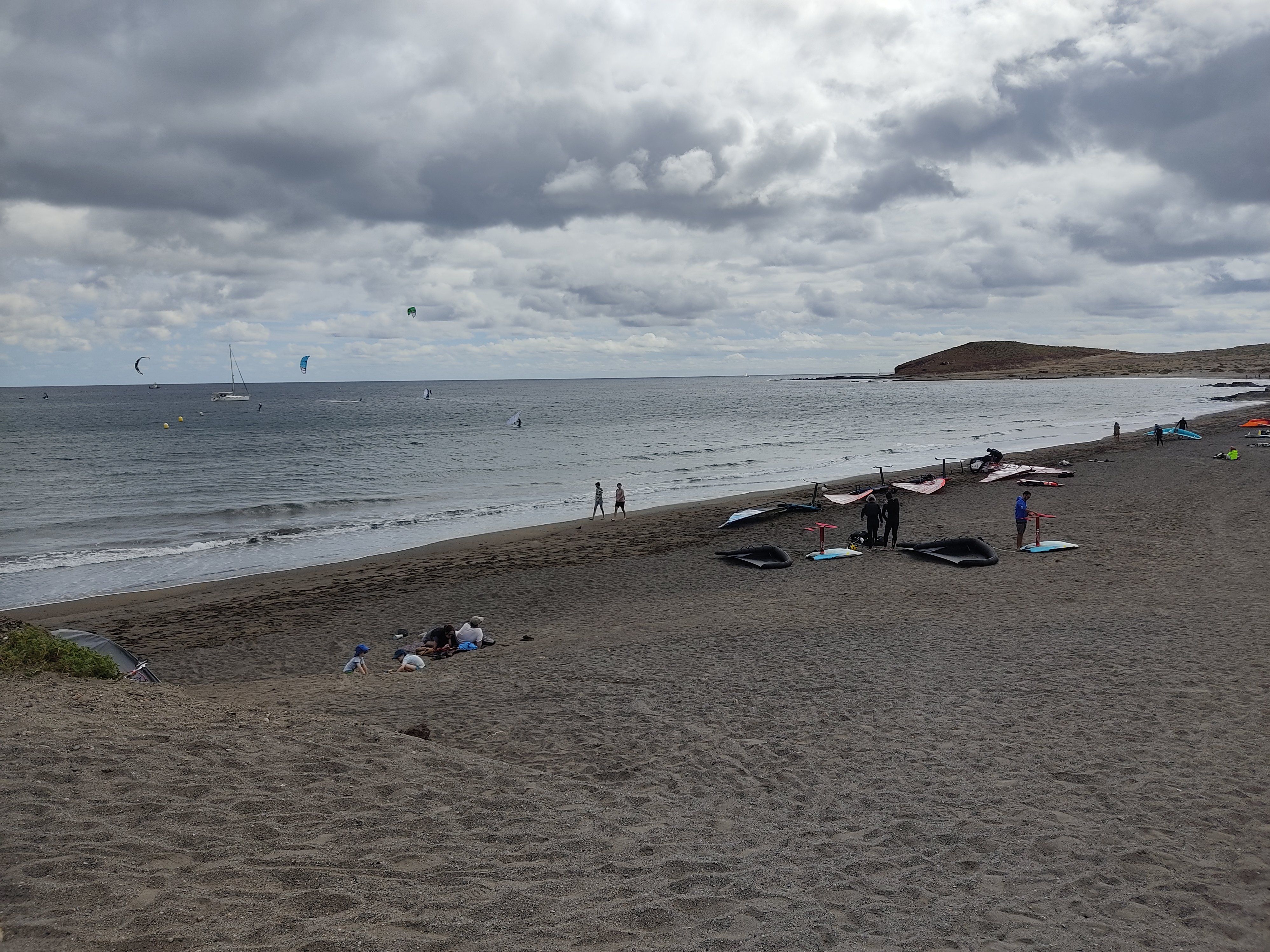 View of El Médano in Tenerife. A few kitesurfers are in the water. A few other ones are on the beach, preparing their kites.